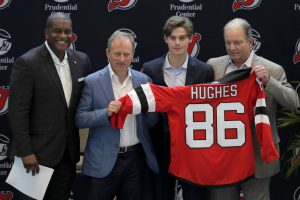 New Jersey Devils forward Jack Hughes, center right, the No. 1 overall pick in the 2019 NHL draft, poses for photographers with former NHL player Kevin Weekes, far left, Josh Harris, second from left, managing partner of Harris Blitzer Sports & Entertainment, and Ray Shero, Devils executive vice president and general manager, during a news conference introducing the prospect to local media, Tuesday, June 25, 2019, in Newark, N.J.